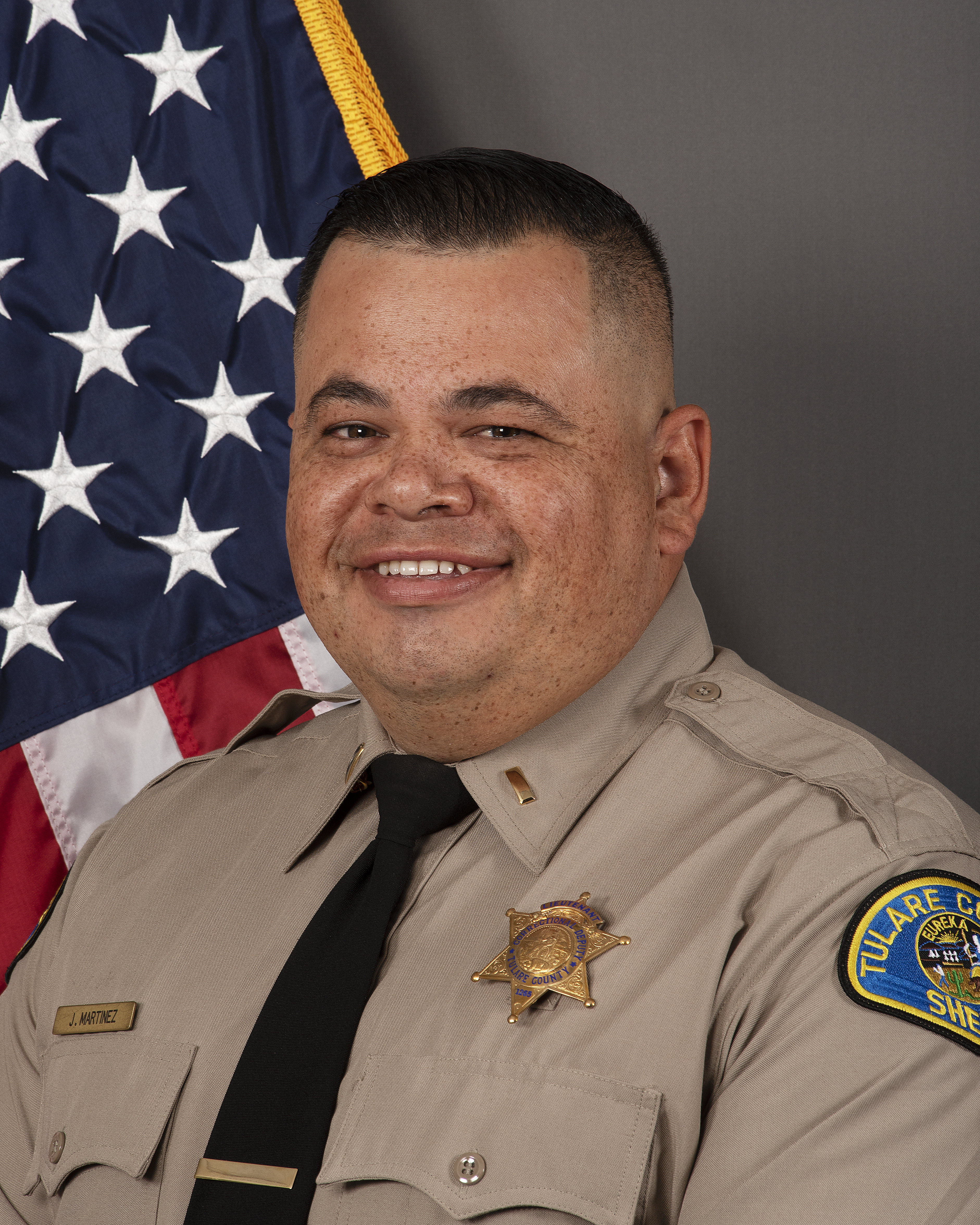 A  head and shoulders portrait of Lt. Javier Martinez in uniform in front of the American Flag.